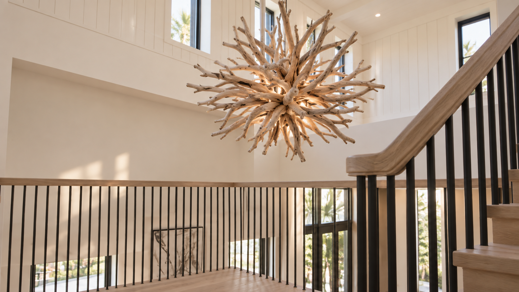 Sculptural driftwood chandelier above a white oak and black iron staircase